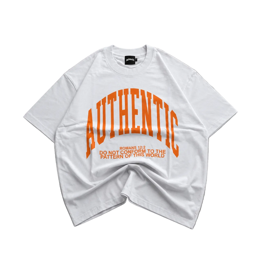 A white oversized short-sleeve t-shirt with a bold orange graphic reading 'AUTHENTIC' and smaller text below, laid flat on a gray concrete surface.